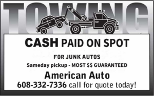 Rear view of a flatbed tow truck with a winch and equipment, ready for service at American Auto Madison, WI.