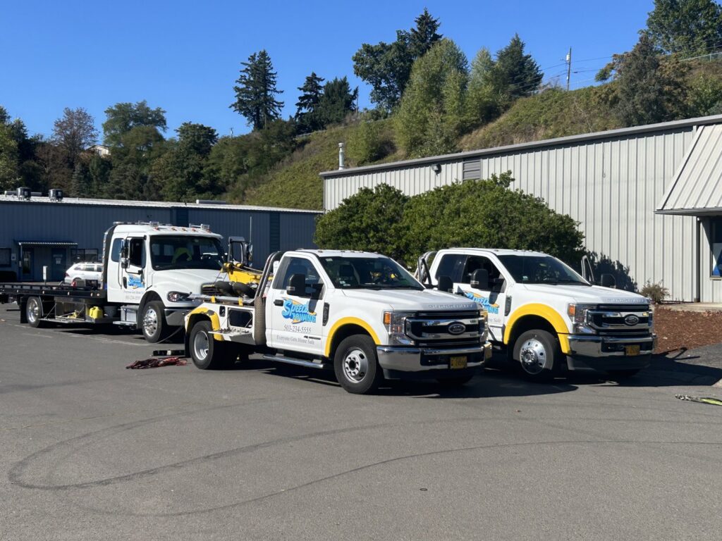 A flatbed tow truck from Speed's Towing transporting a car, alongside other tow trucks in Vancouver, WA.