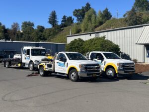 A flatbed tow truck from Speed's Towing transporting a car, alongside other tow trucks in Vancouver, WA.