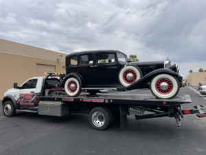 Economy Towing's flatbed truck transporting a classic black vintage car in Las Vegas, NV.
