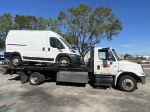 A white flatbed tow truck from Always Ready Towing transporting a white cargo van in North Fort Myers, FL.