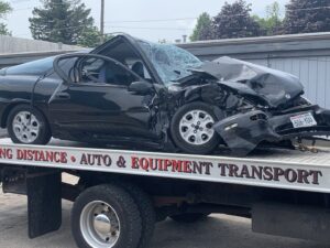 A&W Towing and Repair flatbed tow truck transporting a heavily damaged black car in Appleton, WI.