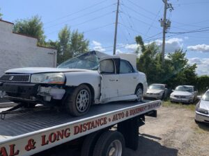 A&W Towing and Repair flatbed tow truck transporting a damaged white car in Appleton, WI.