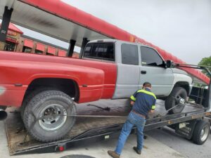 Alliance Towing loading a red and grey pickup truck onto a flatbed tow truck in Lancaster, PA.