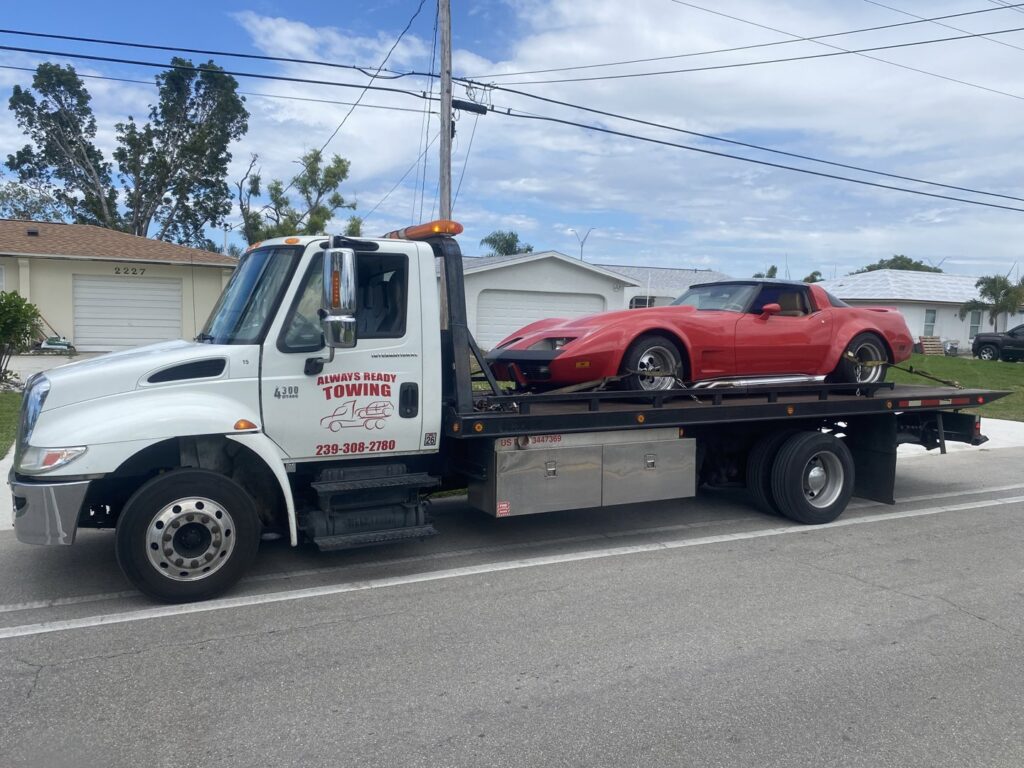 A flatbed tow truck from Always Ready Towing transporting a red classic car in North Fort Myers, FL.