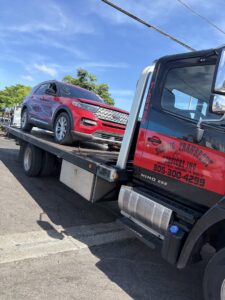 A flatbed tow truck from Rodicio Towing Services transporting a red SUV in Hialeah, FL.