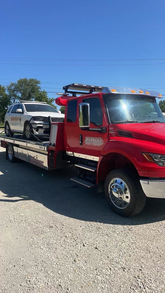 A flatbed tow truck towing a sheriff's SUV for Diversified Towing and Recovery, LLC in Creston, IA.