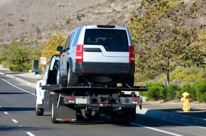 A flatbed tow truck transporting a silver SUV for AE Recovery and Towing in Phoenix, AZ.