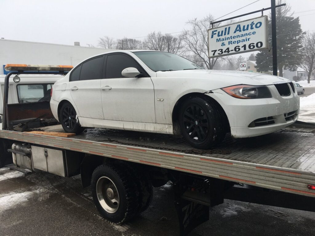 A&W Towing and Repair flatbed tow truck transporting a white BMW sedan in Appleton, WI.