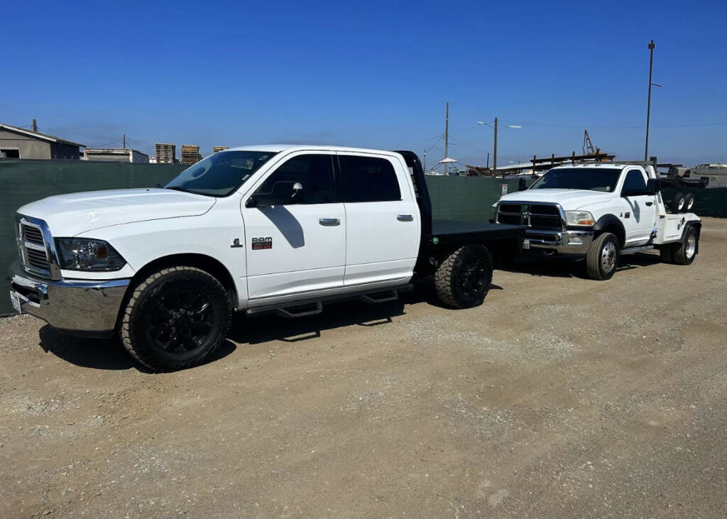 A white flatbed tow truck towing a white wrecker tow truck by Cali kings Towing in San Diego, CA.