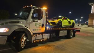 A flatbed tow truck from Allan Motors & Wrecker Service LLC towing a yellow sports car at night in Houston, TX