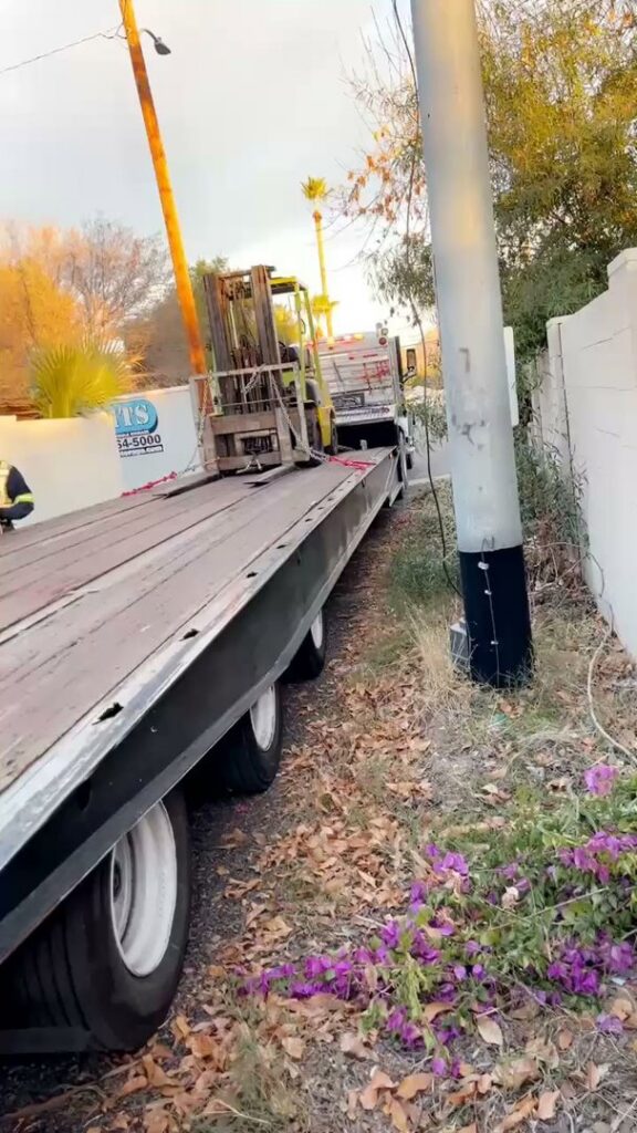 A flatbed trailer transporting a forklift, handled by Power Towing & Transport in Phoenix, AZ.