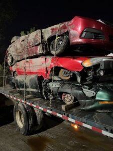 A flatbed truck from ALDM Management loaded with multiple damaged cars at night for removal in Cleveland, OH.