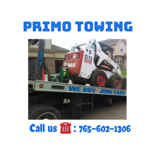 A Primo Towing flatbed truck transporting a Bobcat skid-steer loader in Anderson, IN.