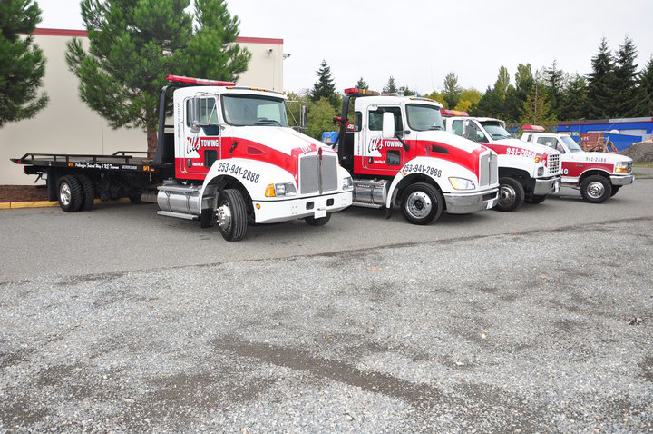 A fleet of Al's Towing flatbed and wrecker trucks parked in Jackson, NJ