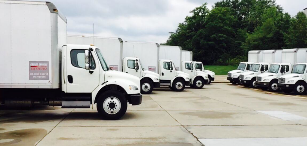 A fleet of white moving trucks parked and ready for service at Empire Express Transport in Cincinnati, OH.