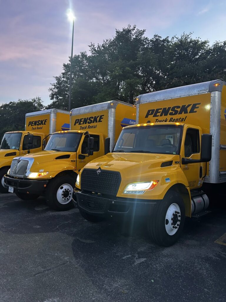A fleet of yellow Penske moving trucks parked, used by The Knoxville Moving Co. for services in Knoxville, TN.