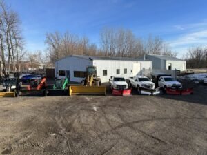A fleet of snow plow trucks and skid steers lined up, ready for snow removal by Pro Cut Lawn Services in Green Bay, WI.
