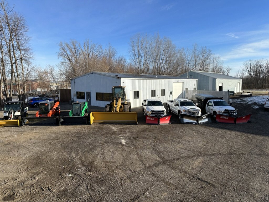 A fleet of snow plow trucks and skid steers lined up, ready for snow removal by Pro Cut Lawn Services in Green Bay, WI.