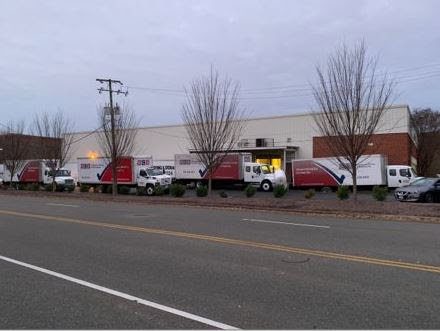A fleet of RCS Moving & Storage trucks parked outside a commercial building in Richmond, VA, ready for service.