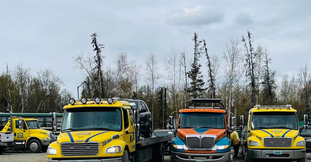 A fleet of Help Line Towing trucks, including a flatbed with a car, ready for service in Wasilla, AK.