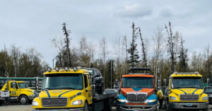 A fleet of Help Line Towing trucks, including a flatbed with a car, ready for service in Wasilla, AK.