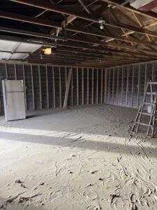 A garage floor covered in sand and debris from flood cleanup by 406 Disaster Response in Billings, MT.