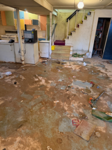 A severely flooded basement with mud and debris on the floor, showing water damage handled by Elam Enterprises in Jonesboro, AR.