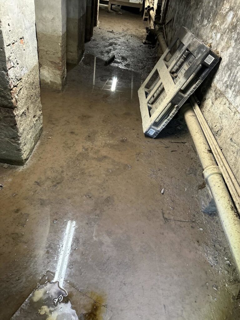 A flooded basement with standing muddy water, indicating severe water damage for RestoPros Hudson County in Jersey City, NJ.