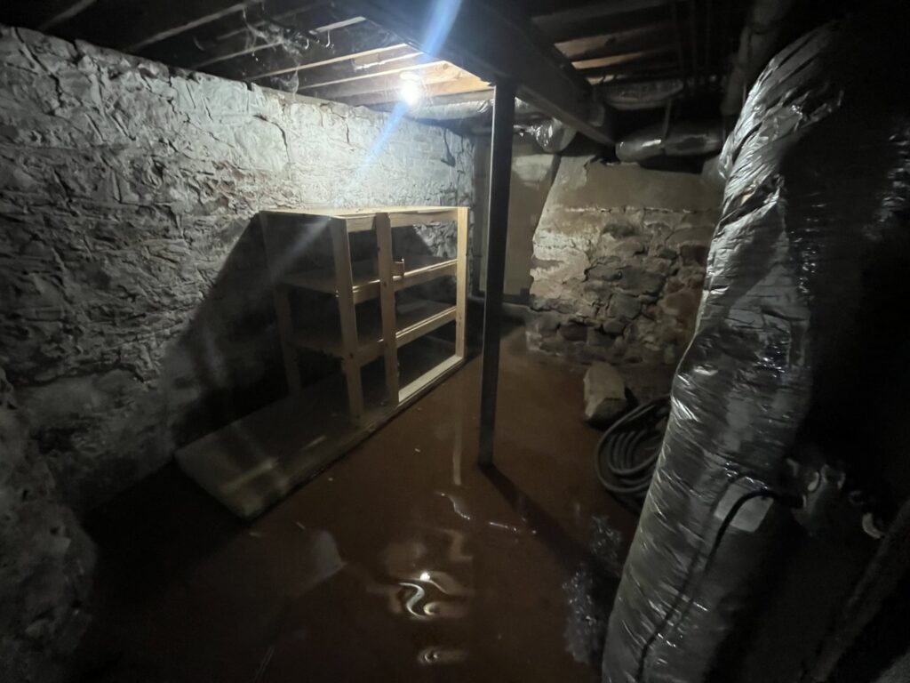 A severely flooded basement with standing muddy water, indicating significant water damage for RestoPros of New Haven in Prospect, CT