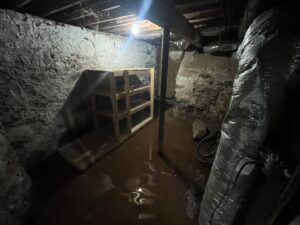 A severely flooded basement with standing muddy water, indicating significant water damage for RestoPros of New Haven in Prospect, CT