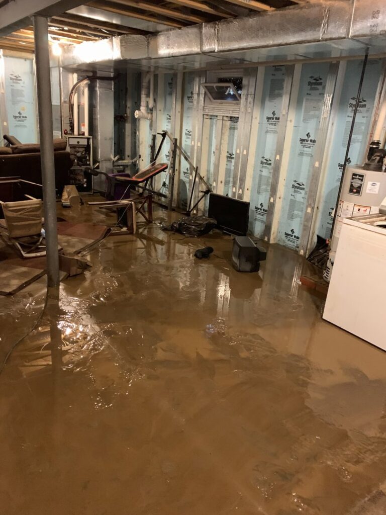 A severely flooded basement with muddy water, requiring immediate water damage cleanup from Prime Restoration in Lancaster, PA.