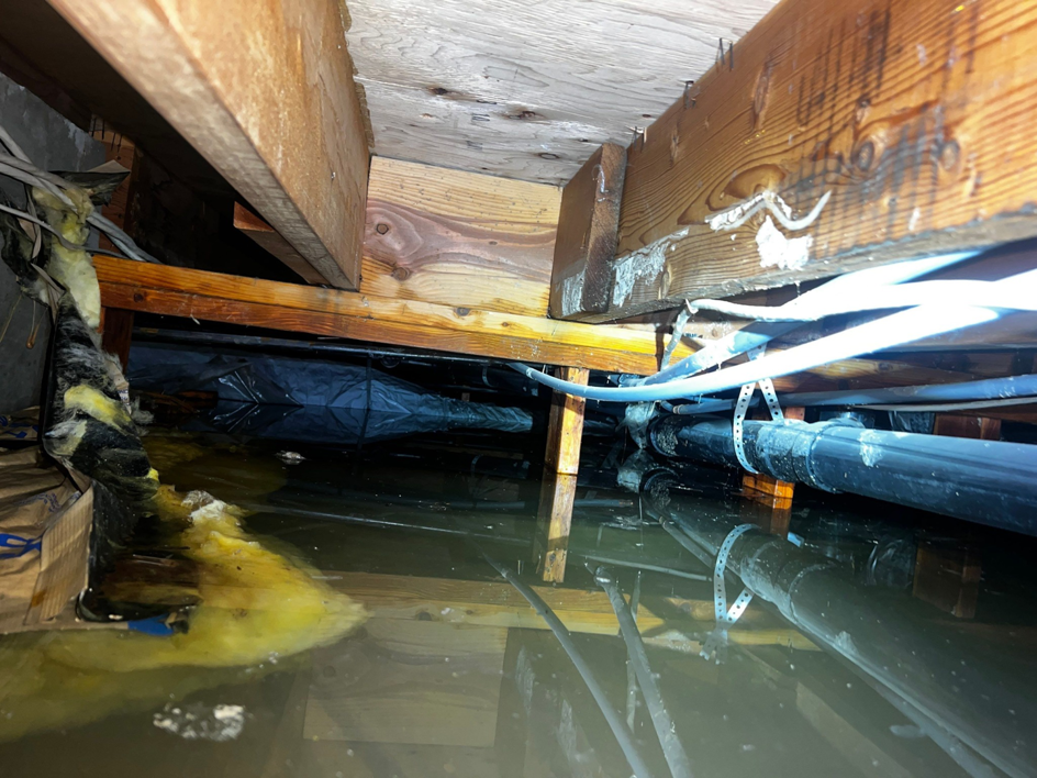 A severely flooded crawl space with standing water and damaged insulation, handled by Peak Performance Restoration in Meridian, ID.