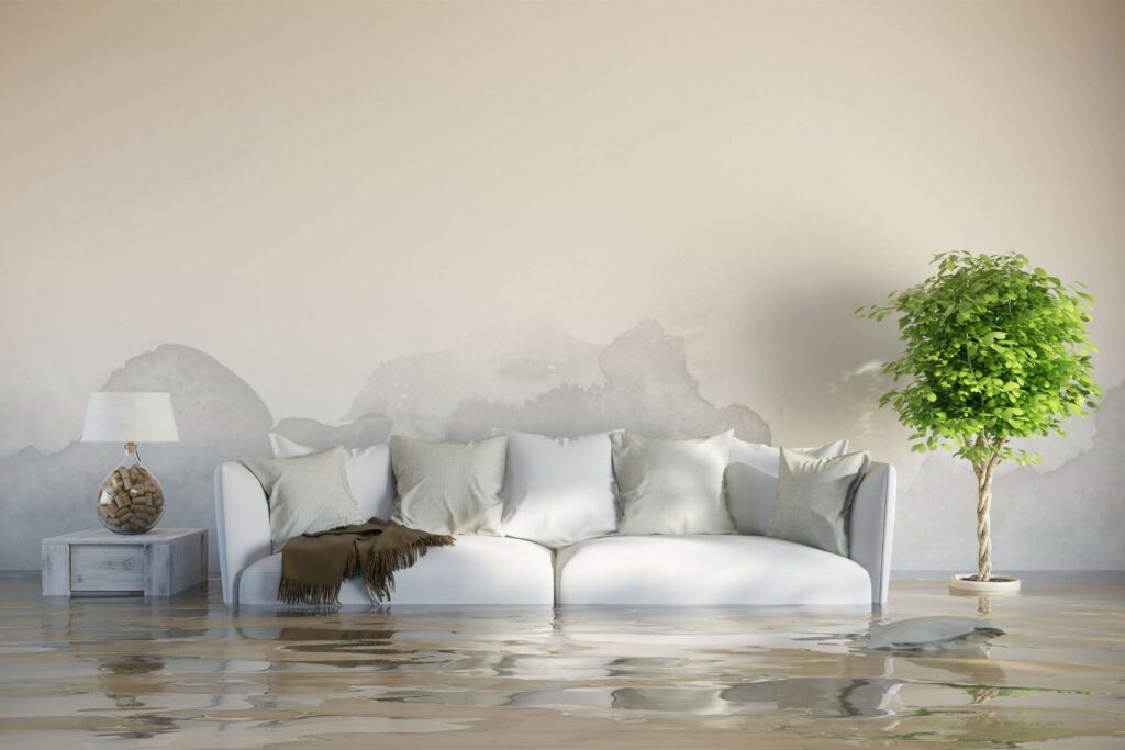 A living room with standing water on the floor and visible water stains on the walls, indicating severe water damage, handled by Absolute Water Mitigation & Restoration in Greeley, CO