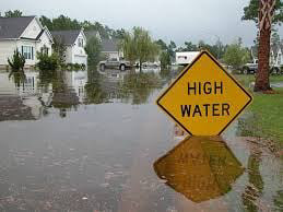 A "HIGH WATER" sign in a flooded residential street, indicating severe water damage needing 1st Choice Fire and Water Restoration in South Bend, IN.