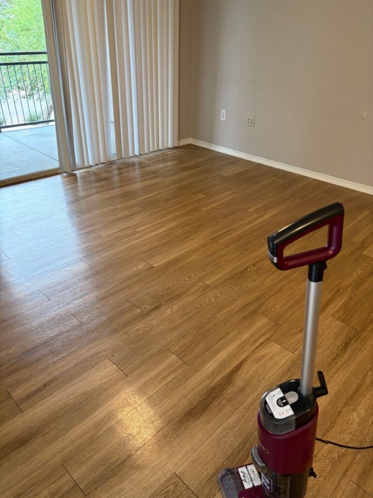 A floor cleaning machine positioned on a freshly cleaned wooden floor in an empty room, showcasing the tools used by CleanCo Works in Scottsdale, AZ.