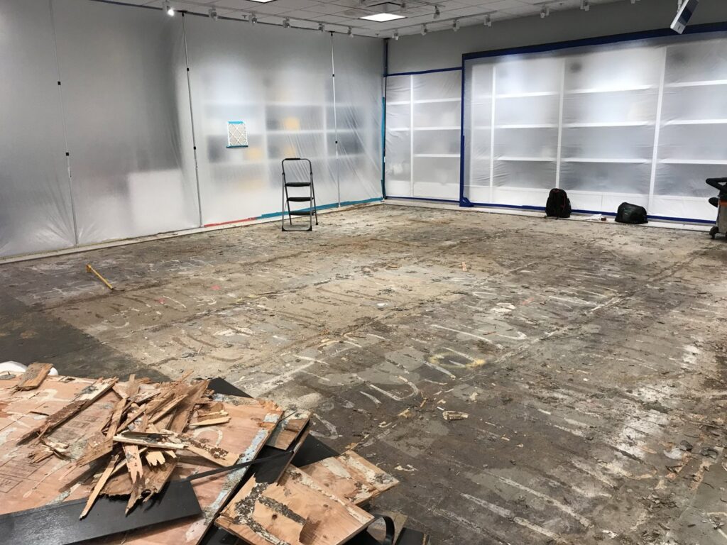 A large room with flooring removed and plastic containment, showing demolition for water damage restoration by Island Restoration LLC in Kapolei, HI.