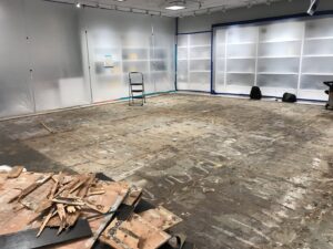 A large room with flooring removed and plastic containment, showing demolition for water damage restoration by Island Restoration LLC in Kapolei, HI.