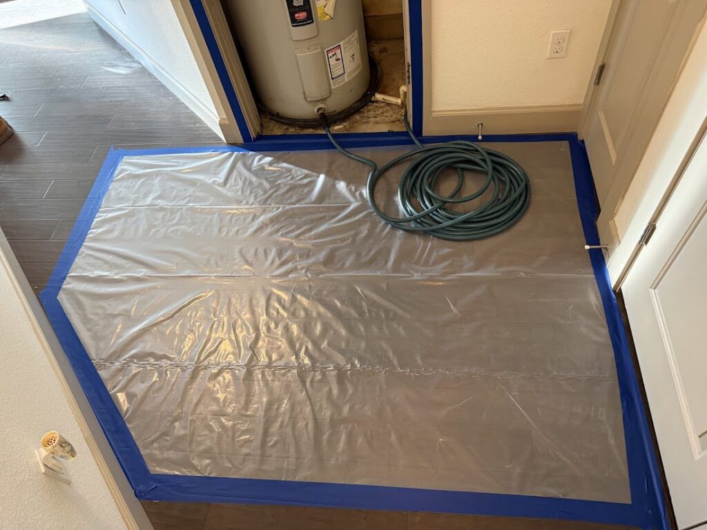 Floor protection laid out near a water heater, preparing for water damage work by Flow State Restoration in Gilbert, AZ