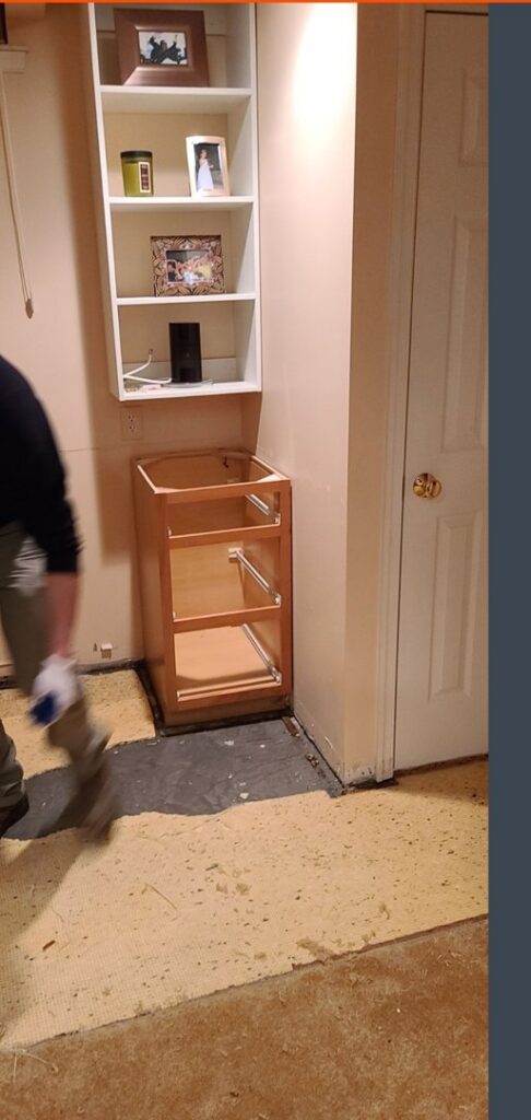 A worker removing damaged flooring in a basement during water damage restoration by 1d Remedy LLC in Mechanicsburg, PA
