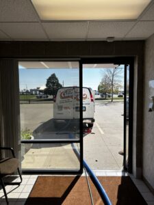 The FM Cleaning van parked outside a commercial building with a cleaning hose extended inside in West Fargo, ND.