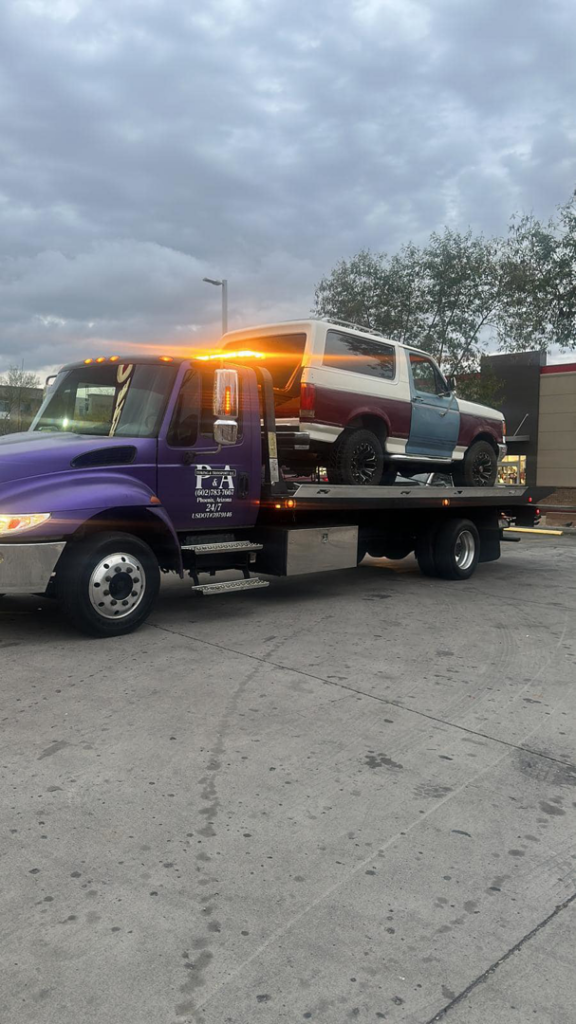 A two-tone Ford Bronco being transported on a flatbed tow truck by P&A towing & transport Llc in Phoenix, AZ