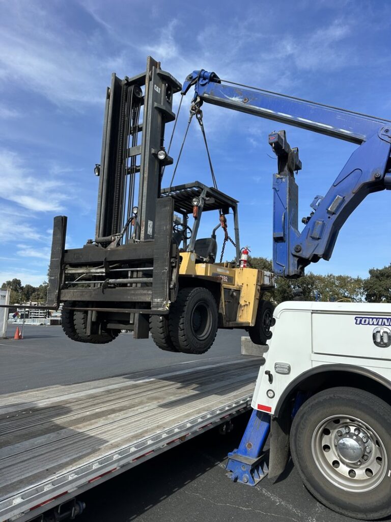 AJ's Towing Services & Roadside Assistance using a heavy wrecker to load a forklift for transport in Sacramento, CA.