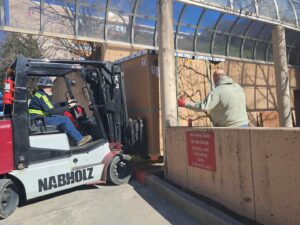 A forklift moving a large wooden crate, demonstrating heavy item handling by Peroulas Moving and Storage in Knoxville, TN