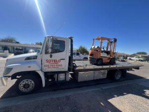 Sotelo Towing LLC providing heavy equipment towing for an orange forklift in Phoenix, AZ.