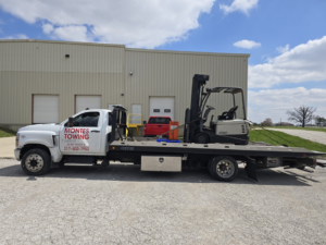 A forklift being transported on a Montes Towing Services flatbed truck in Indianapolis, IN.