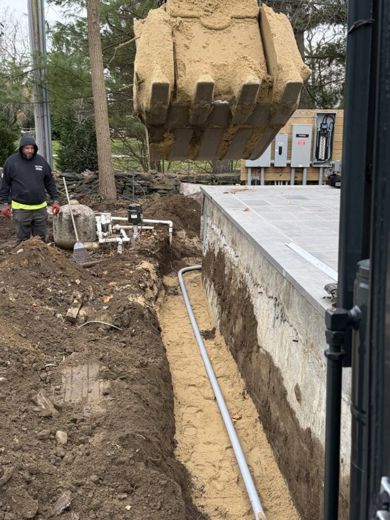 A worker installing drainage pipes next to a building foundation for Fleury Dirt Works & Services Llc in Cumberland, RI