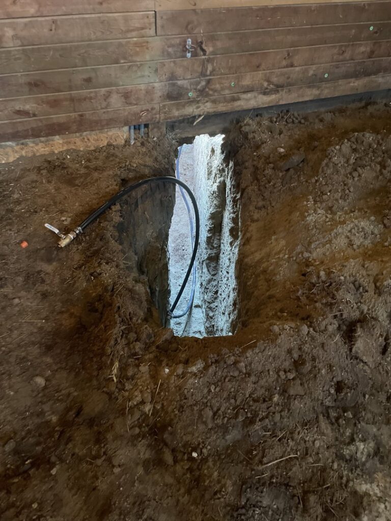 Foundation drainage pipe installation in a trench next to a building by KD Services - Excavating in Bismarck, ND