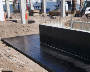 Foundation slab and wall coated with a black waterproofing membrane by Proshield Waterproofing & Restoration in Overland Park, KS