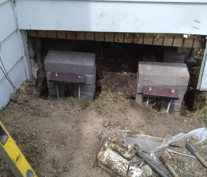 Foundation underpinning and repair work with concrete blocks and metal supports by Fort Wayne Foundation Repair Experts in Fort Wayne, IN.